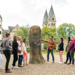 Reisegruppe Stadtführer Daumstatue Basilika St. Kastor Deutschherrenhof Koblenz © Koblenz-Touristik GmbH, Dominik Ketz Reisegruppe hört einem Stadtführer zu, während er eine große Daumenstatue vor dem Ludwigmuseum erklärt © Koblenz-Touristik GmbH, Dominik Ketz