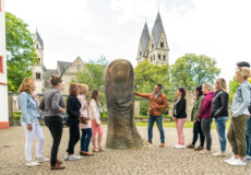 Reisegruppe hört einem Stadtführer zu, während er erklärt eine große Daumstatue vor dem Ludwigmuseum © Koblenz-Touristik GmbH, Dominik Ketz Reisegruppe hört einem Stadtführer zu, während er erklärt eine große Daumstatue vor dem Ludwigmuseum © Koblenz-Touristik GmbH, Dominik Ketz