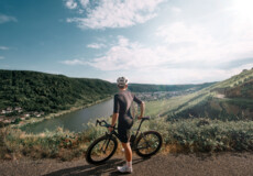 Man sieht einen Mountainbike-Fahrer von hinten, der in die Ferne auf die Mosel und die Weinberge blickt © Koblenz-Touristik GmbH, Philip Bruederle Man sieht einen Mountainbike-Fahrer von hinten, der in die Ferne auf die Mosel und die Weinberge blickt © Koblenz-Touristik GmbH, Philip Bruederle
