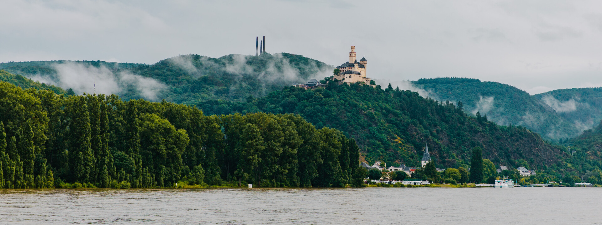 Blick auf die Marksburg vom Rheinufer umgeben von Bergen und Wald mit dem Rhein im Vordergrund © Koblenz-Touristik GmbH, Henry Tornow Blick auf die Marksburg vom Rheinufer umgeben von Bergen und Wald mit dem Rhein im Vordergrund © Koblenz-Touristik GmbH, Henry Tornow