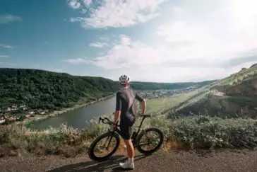 Man sieht einen Mountainbike-Fahrer von hinten, der in die Ferne auf die Mosel und die Weinberge blickt