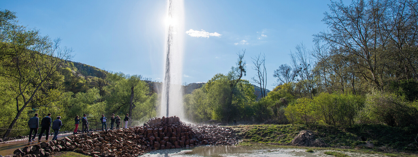 © Geysir.info GmbH, Klaus-Peter Kappes Geysir Andernach hinterbeleuchtet von der Sonne mit beobachtenden Menschen im Vordergrund © Geysir.info GmbH, Klaus-Peter Kappes