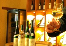 Verkaufsraum einer Vinothek mit vier Flaschen Wein, die auf einem Fass präsentiert werden © Koblenz-Touristik GmbH