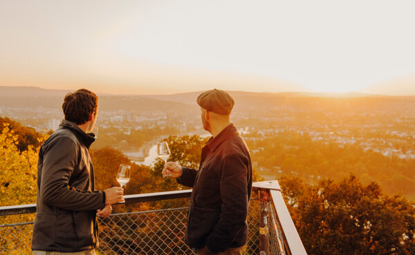 Zwei Männer im Abendlicht mit Weingläsern auf einer Aussichtsplattform mit Blick auf den Zusammenfluss von Rhein und Mosel © Koblenz-Touristik GmbH, Philipp Bruederle Zwei Männer im Abendlicht mit Weingläsern auf einer Aussichtsplattform mit Blick auf den Zusammenfluss von Rhein und Mosel © Koblenz-Touristik GmbH, Philipp Bruederle