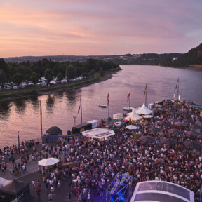 Electronic Wine © Picture Colada Blick von oben auf das Deutsche Eck bei Abenddämmerung während einer Veranstaltung, Menschengruppen stehen vor einer Bühne und an Ständen verteilt auf dem Gelände © Picture Colada