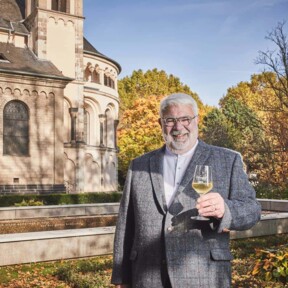 © Koblenz-Touristik GmbH, Picture Colada Lächelnder Stadtführer Michael Hörter mit einem Glas Wein in der Hand steht vor dem Basilika St. Kastor im Herbst © Koblenz-Touristik GmbH, Picture Colada