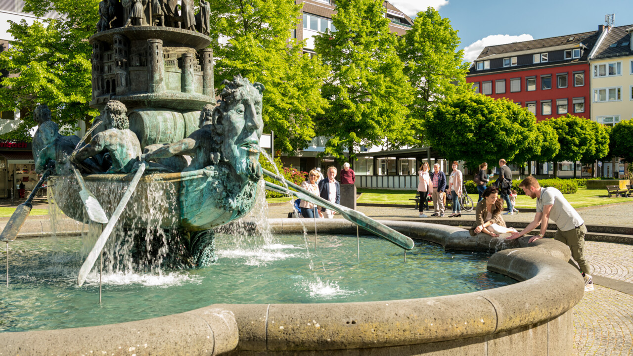 Brunnen Historiensäule Görresplatz Koblenz © Koblenz-Touristik GmbH, Dominik Ketz Brunnen "Historiensäule" auf dem Görresplatz in Koblenz umgeben von kleinen Menschengruppen © Koblenz-Touristik GmbH, Dominik Ketz