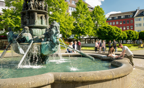 Brunnen "Historiensäule" auf dem Görresplatz in Koblenz umgeben von kleinen Menschengruppen © Koblenz-Touristik GmbH, Dominik Ketz Brunnen "Historiensäule" auf dem Görresplatz in Koblenz umgeben von kleinen Menschengruppen © Koblenz-Touristik GmbH, Dominik Ketz