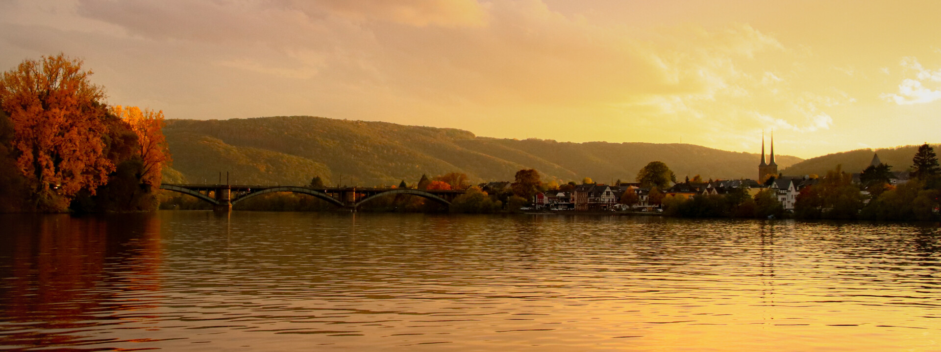 Mosel bei Sonnenuntergang © Johannes Bruchhof Blick über die Mosel bei Sonnenuntergang, im Hintergrund ein kleiner Ort mit Kirchturmspitze © Johannes Bruchhof