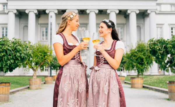 Weinmajestäten Weinfest Lay 2022_Schlossgarten © Koblenz-Touristik GmbH, Tibor Resch Zwei junge Frauen in festlichen Kleidern, mit Diadem und Weingläsern in der Hand, im Hintergrund das kurfürstliche Schloss in Koblenz © Koblenz-Touristik GmbH, Tibor Resch
