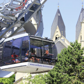 © Koblenz-Touristik GmbH Kabine der Seilbahn Koblenz mit Passagieren. Türme der Basilika St. Kastor im Hintergrund © Koblenz-Touristik GmbH