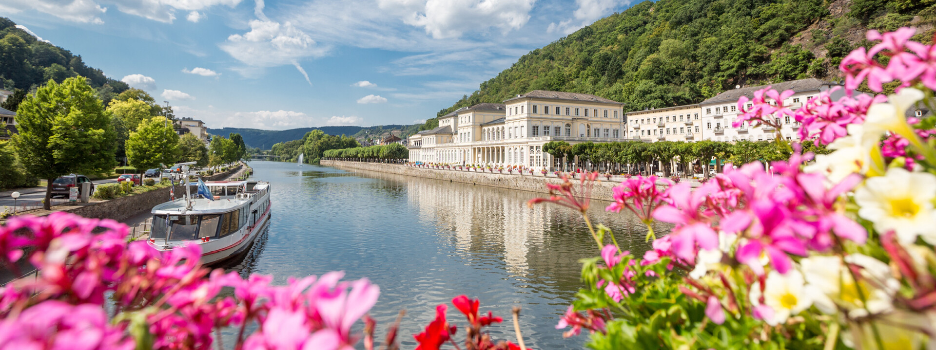 Bad Ems Lahn pinke Blumen ©  Pinke Blumen bluten vor der Lahn mit romantischen Gebäuden und einem kleinen Schiff im Hintergrund ©