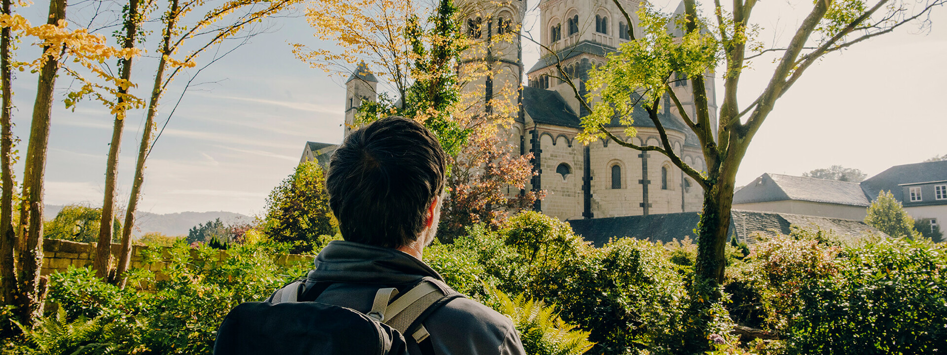Maria Laach Abteikirche © Koblenz-Touristik GmbH, Philip Bruederle Mann von hinten blickt auf das Kloster Maria Laach im Herbst © Koblenz-Touristik GmbH, Philip Bruederle