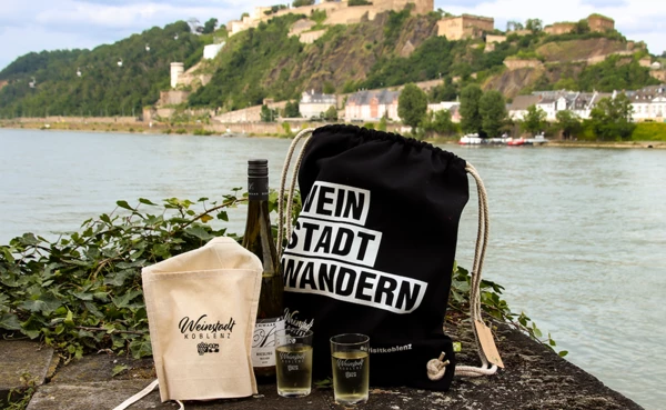 Zwei Mädels sitzen auf der Wiese vor dem preußischen Regierungsgebäude mit einem Glas Wein in der Hand und lachen. Der WeinStadtWander-Beutel steht vor ihnen auf der Wiese. © Koblenz-Touristik, Johannes Bruchhof Zwei Mädels sitzen auf der Wiese vor dem preußischen Regierungsgebäude mit einem Glas Wein in der Hand und lachen. Der WeinStadtWander-Beutel steht vor ihnen auf der Wiese. © Koblenz-Touristik, Johannes Bruchhof