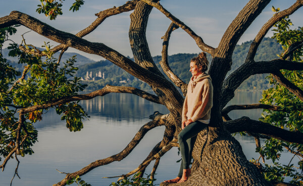 Frau Baum im Wasser Maria Laach © Koblenz-Touristik GmbH, Philip Bruederle Dame von Seite blickt auf den Sonnenaufgang bei Maria Laach mit dem Kloster und See im Hintergrund © Koblenz-Touristik GmbH, Philip Bruederle