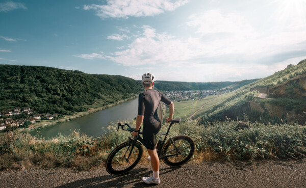 Man sieht einen Mountainbike-Fahrer von hinten, der in die Ferne auf die Mosel und die Weinberge blickt © Koblenz-Touristik GmbH, Philip Bruederle