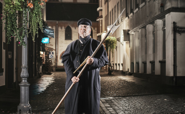 211015_Koblenz_Touristik_v001_1_NM_8Z5A3439.jpg ©  Ein Stadtführer verkleidet als Nachtwächter steht vor einer Straßenlaterne ©