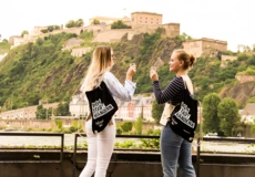 Zwei junge Frauen prosten sich beim WeinStadtWandern am Rhein mit Blick auf die Festung Ehrenbreitstein zu. © Koblenz-Touristik, Johannes Bruchhof Freundinnen stoßen Weingläsern beim WeinStadtWandern © Koblenz-Touristik, Johannes Bruchhof