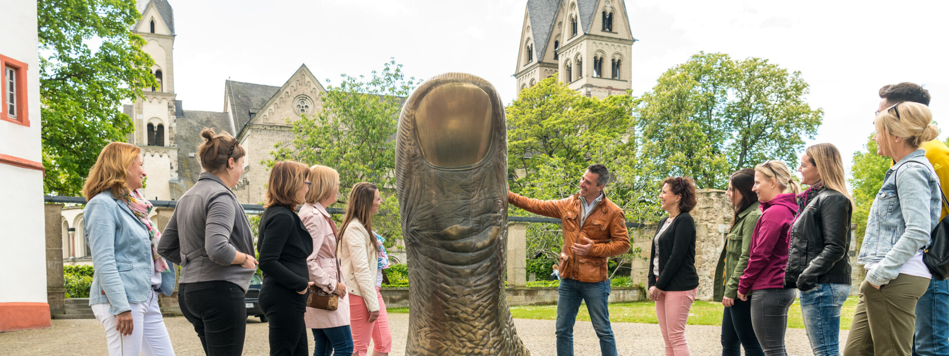 Tour group listens to a city guide as he explains a large statue of a thumb in front of the Ludwig Museum © Koblenz-Touristik GmbH, Dominik Ketz Tour group listens to a city guide as he explains a large statue of a thumb in front of the Ludwig Museum © Koblenz-Touristik GmbH, Dominik Ketz