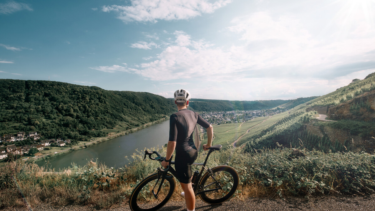 Man sieht einen Mountainbike-Fahrer von hinten, der in die Ferne auf die Mosel und die Weinberge blickt © Koblenz-Touristik GmbH, Philip Bruederle